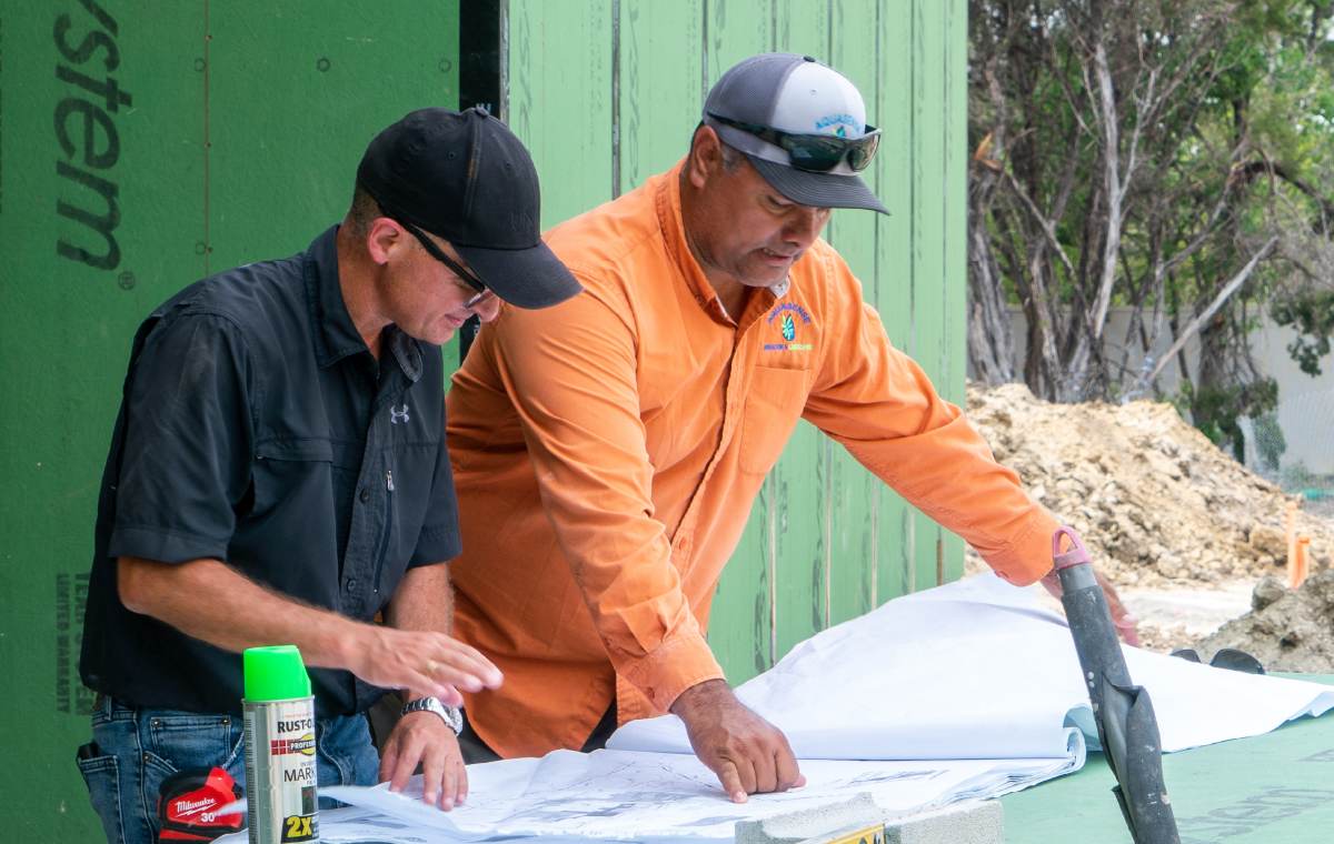 Image of two male construction workers looking over a blueprint together.