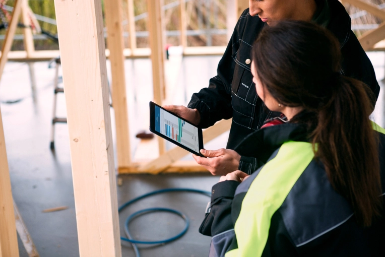 Two people at construction site looking at tablet